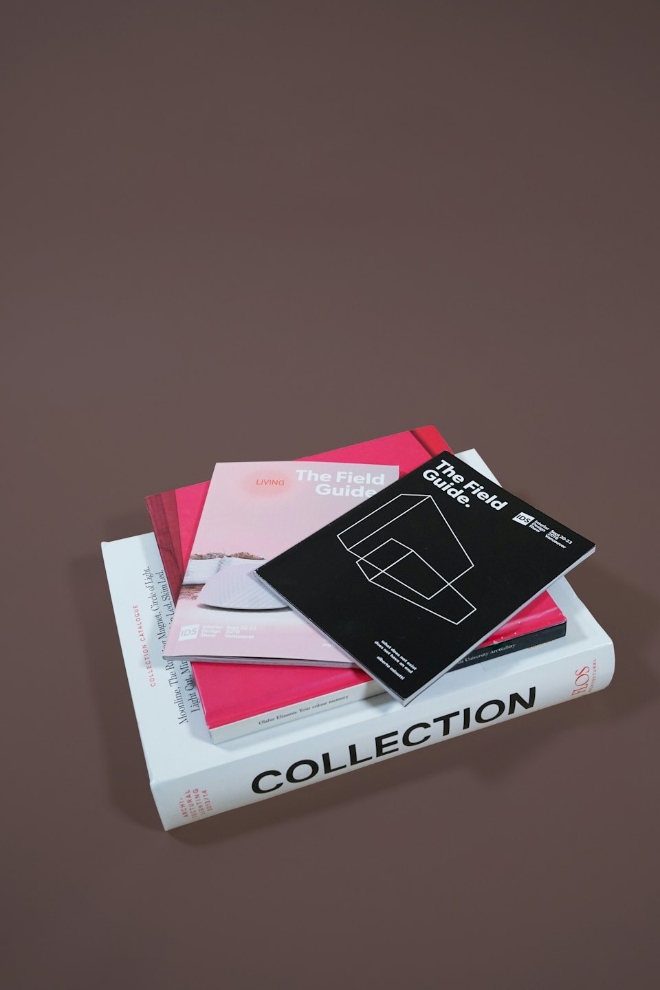 Stack of design books and magazines on a light brown surface.
