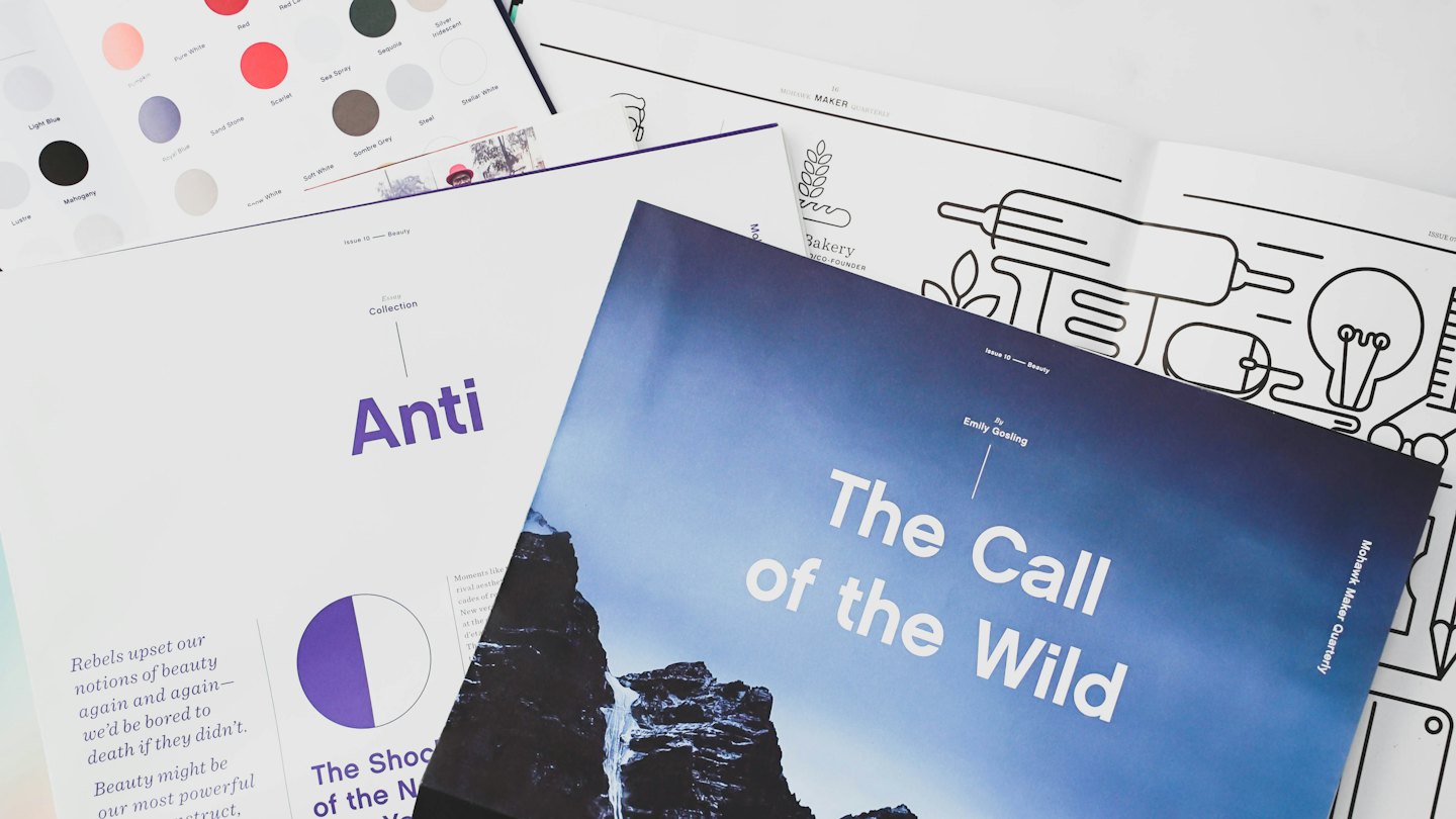 Printed magazines and color swatches arranged on a white surface.
